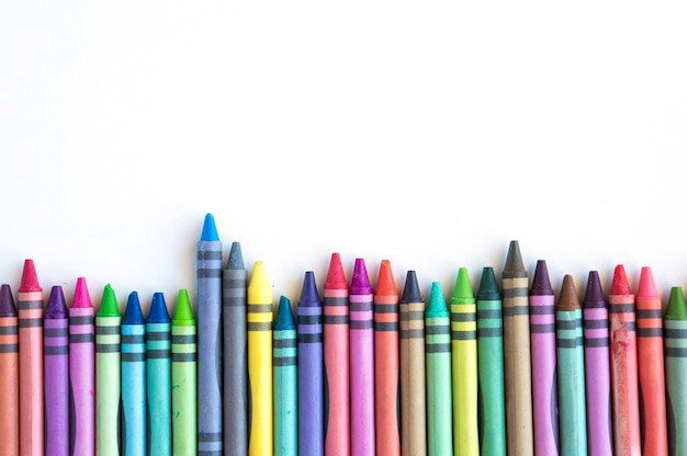 Crayons and pastels lined up in rainbow isolated on white background