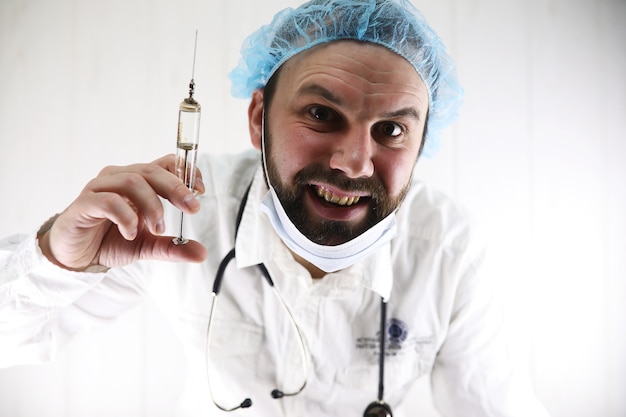 Crazy bearded doctor in a white coat and an old syringe