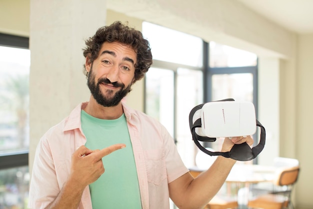 crazy bearded man smiling cheerfully feeling happy and pointing to the side vr goggles concept