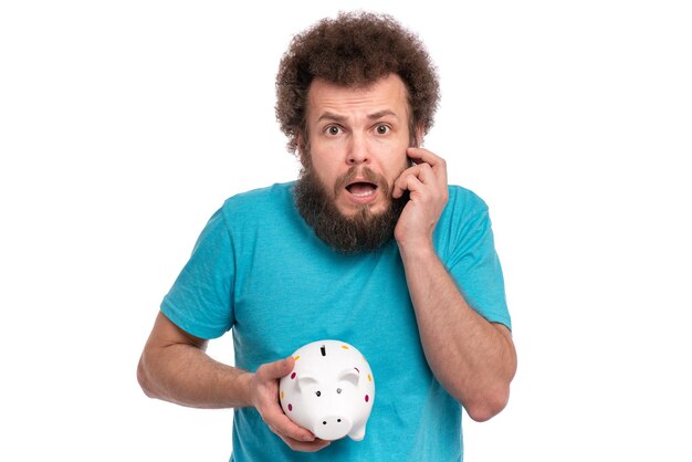 Crazy bearded Man with funny Curly Hair holding Piggy Bank isolated on white background