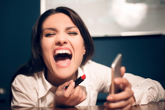 Photo crazy cheerful woman applying lipstick.