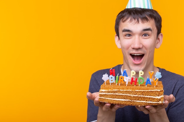 Сумасшедший жизнерадостный молодой человек в очках и бумажных поздравительных шляпах держит торты с днем рождения
