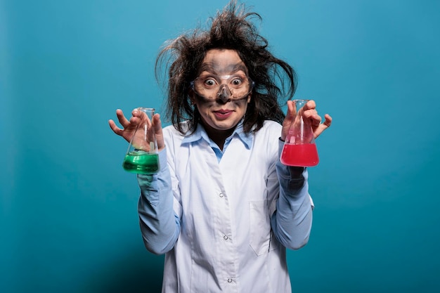 Chimico pazzo che tiene boccette di vetro piene di composti chimici tossici dopo l'esplosione di laboratorio. lavoratore di laboratorio pazzo e stravagante con bicchieri pieni di sostanze liquide dopo un esperimento di laboratorio fallito