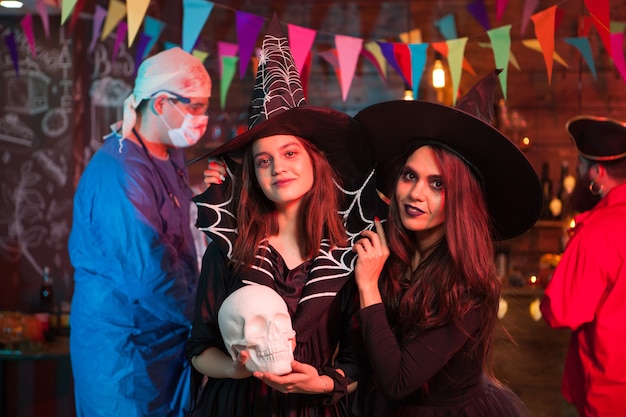 ハロウィーンパーティーで2人の美しい魔女の後ろに血を持った狂った医者。ハロウィーンの伝統。