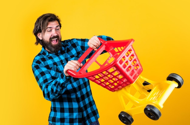 Crazy driver handsome hipster wear checkered shirt in shop mature shopper go shopping in mall bearded man carry shopping cart brutal guy making purchase male fashion style