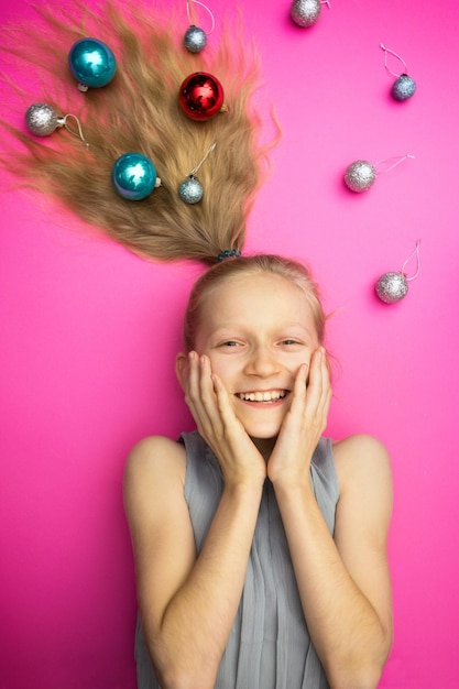 Crazy happy and bright New Years holiday. girl with christmas balls on pink background