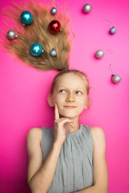 Crazy happy and bright New Years holiday. girl with christmas balls on pink background