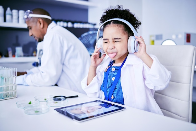 Crazy lab and child with music and tablet for science with a father or scientist for work or learning Funny future and a comic girl streaming audio on tech with a person for innovation in medicine