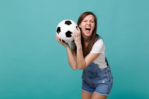 Crazy screaming woman football fan cheer up support favorite team with soccer ball isolated on blue turquoise background. people emotions, sport family leisure lifestyle concept. mock up copy space.