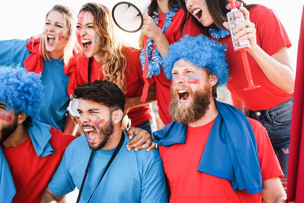 Photo crazy sport fans screaming while supporting their team - focus on center man face