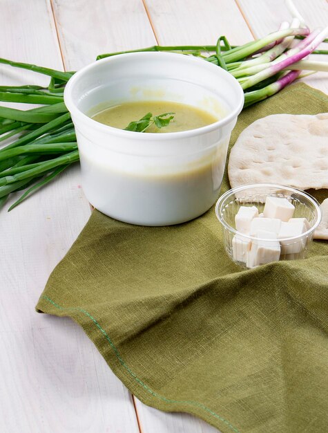 흰색 배경에 있는 용기에 페타 치즈와 토르티야를 넣은 크림 브로콜리 수프 테이크어웨이 다이어트 및 건강 식품