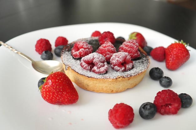 cream cakes with raspberries and blueberries a set of different glazed in black chocolate with custa