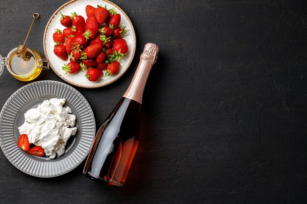 Cream cheese and fresh strawberries on black background close up