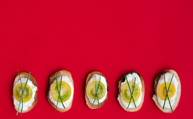 Cream cheese slices of cherry tomatoes and chive on slices of toasted bread