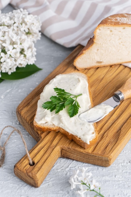 Photo cream cheese with herbs and seasoning on slice of fresh crunchy rye bread with cheese knife nearby