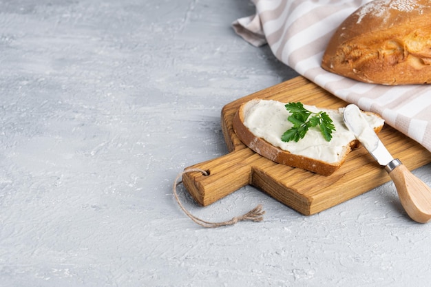 Photo cream cheese with herbs and seasoning on slice of fresh crunchy rye bread with cheese knife nearby