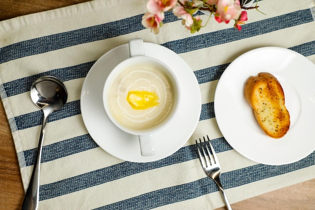 Cream chicken soup with bread served in bowl isolated on napkin top view of chinese soup