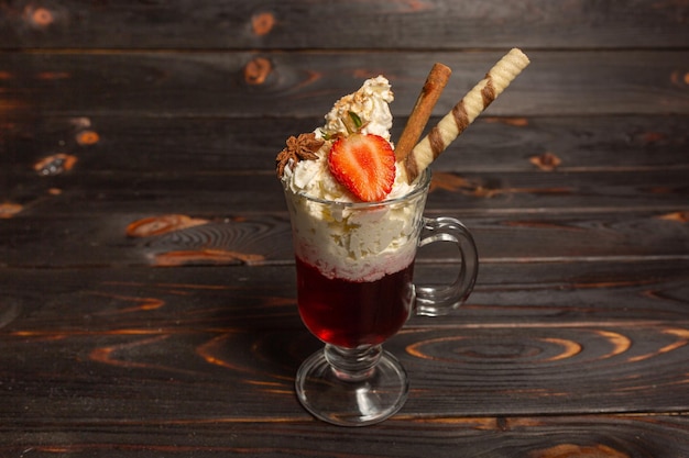 Cream and fresh strawberries in a glass on a dark background