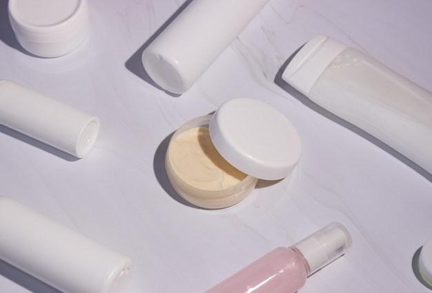 Cream in a jar with an open lid and bottles for cosmetics