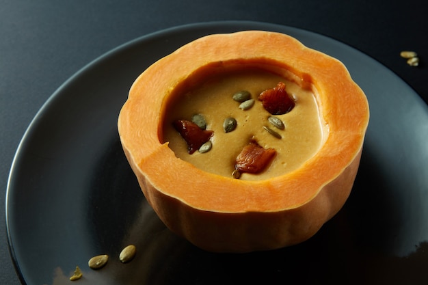 Cream of pumpkin soup with pumpkin seeds and bacon in hollowed-out pumpkin