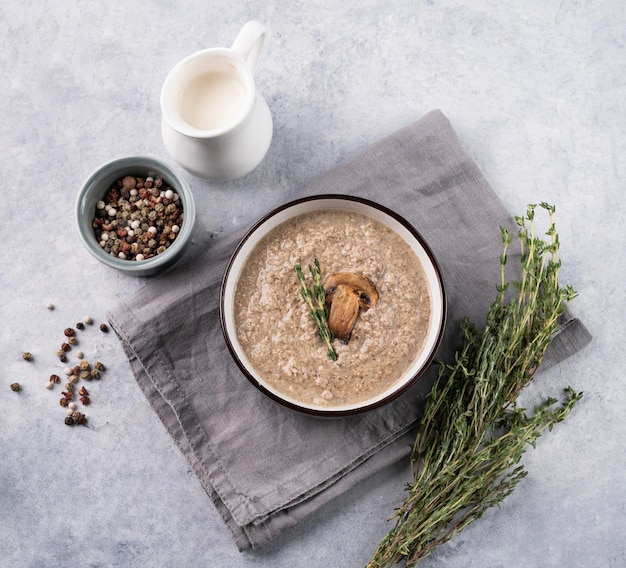 Cream soup of champignons with thyme in a ceramic bowl on a light background with spice and fresh herb The concept of healthy and diet food