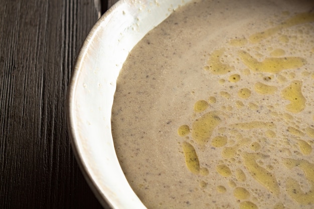 Cream soup of champignons on a wooden table with bread chips close-up