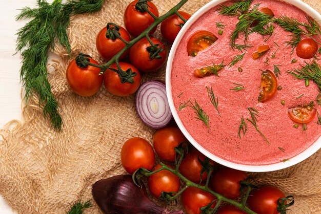 Cream soup of cherry tomatoes with herbs and onions on a wooden
table. vegetarian food. dishes made from natural products. copy
space.