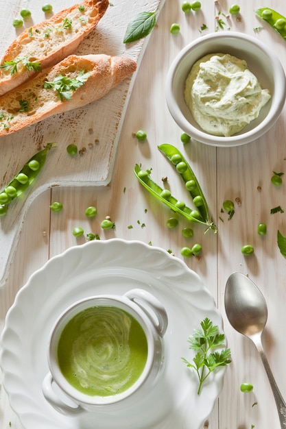 Cream soup of fresh green peas with spicy sauce and dried white bread 
