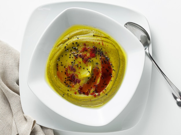 Cream soup with broccoli and potatoes, served with smoked paprika and black sesame seeds isolated on white, top view