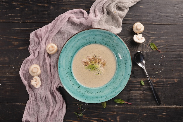 Cream soup with mushrooms. In a blue plate on a wooden table with decor