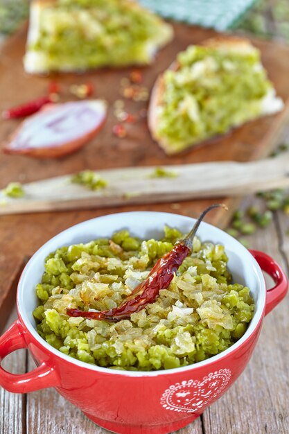 Cream of split green peas with sauce of oil and onions inside small pot and spread over bread slices.