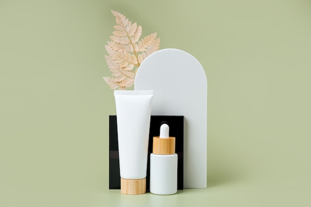 Cream tube and dropper mockup with leaf and geometrical forms on green background