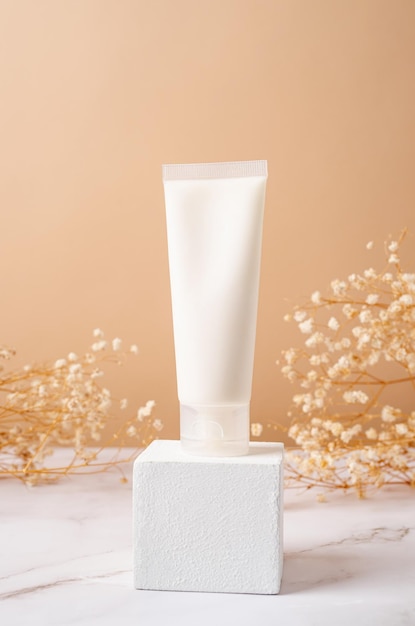 Мокет кремовой трубки для презентации брендинга натурального продукта красоты для ухода за кожей на квадратном белом подиуме