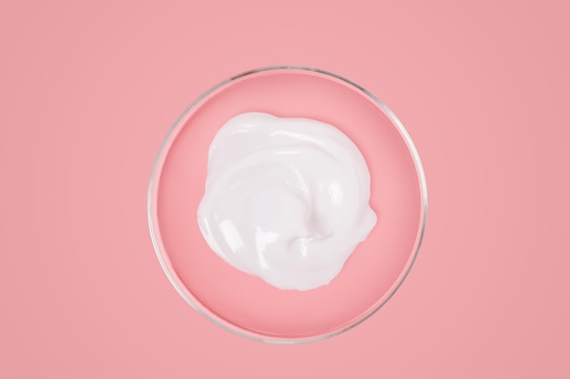 Cream of white color in a petri dish on a pink background View from above