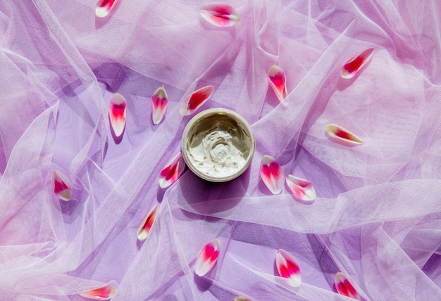 Cream with tulips petals on purple tulle. Natural light