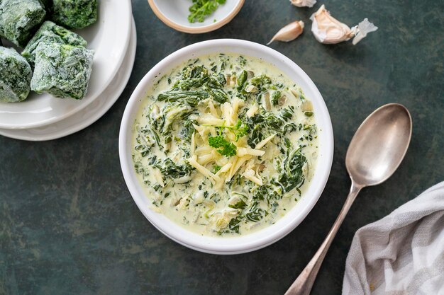 Creamed spinach with cheese in white bowl on dark background Healthy foods