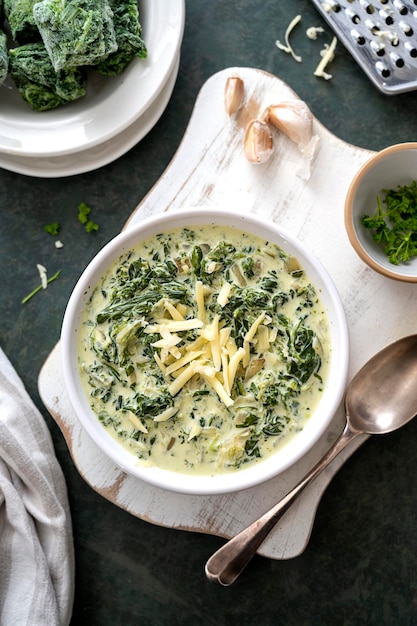 Foto crema di spinaci con aglio e formaggio in una ciotola bianca su sfondo scuro