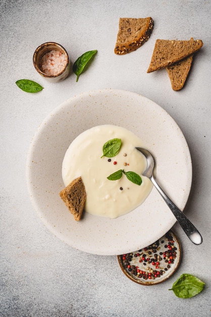 Creamy cauliflower soup with toasted breadon white background top view