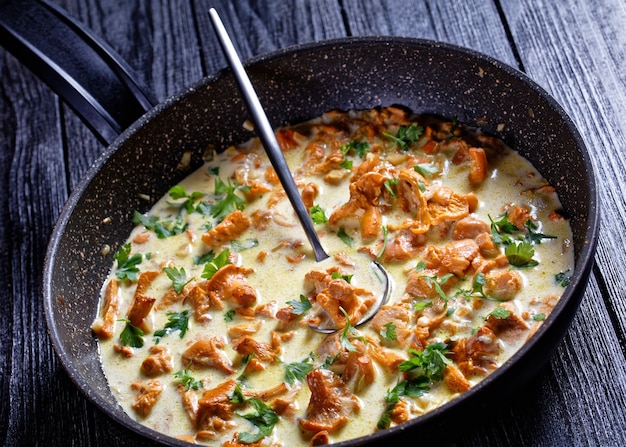 Creamy chanterelle sauce in a pan on a wooden kitchen table, french cuisine, horizontal view from above