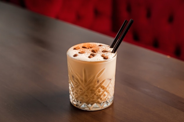 A creamy coffee alcoholic cocktail in a rocks, lowball, old fashioned glass, garnished with coffee beans