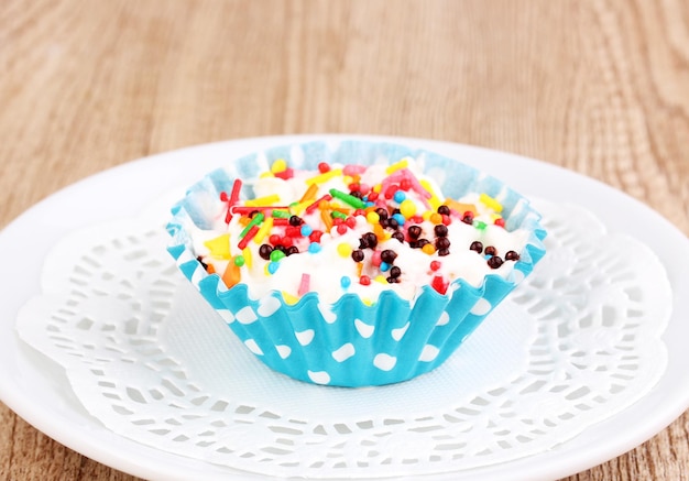 Creamy cupcake on saucer on wooden background