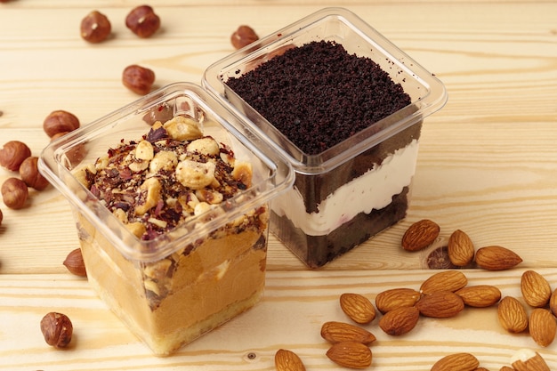 Creamy dessert in a plastic box on wooden table, close up