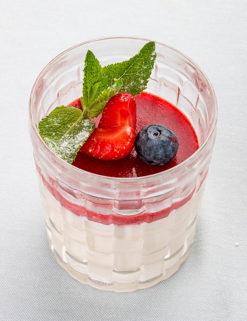 Creamy dessert with strawberry jelly and berries on white background