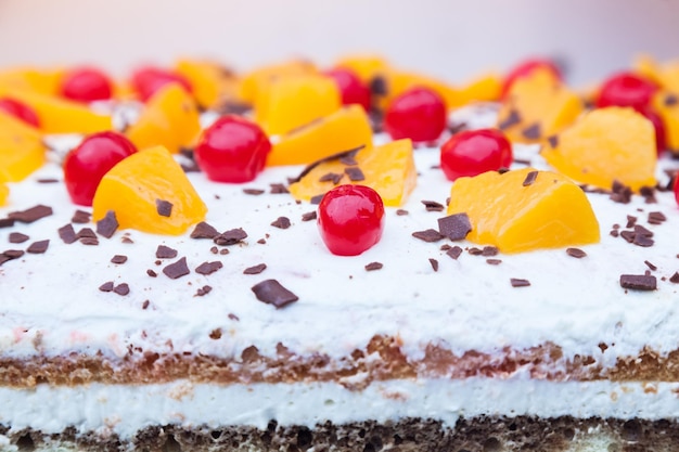 Creamy layered cake with chocolate cherry and peach chunks on top