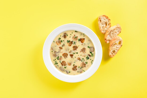 Creamy mushroom soup over yellow background Top view flat lay