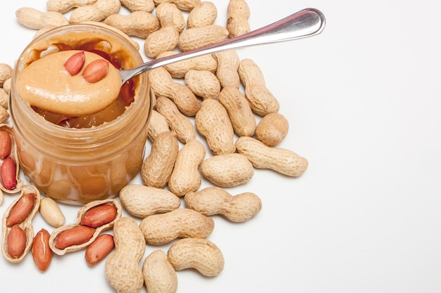 Creamy peanut butter in glass jar peanut and spoon isolated on white background A traditional product of American cuisine