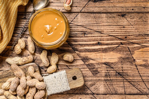 Creamy peanut butter in jar on wood table, organic food