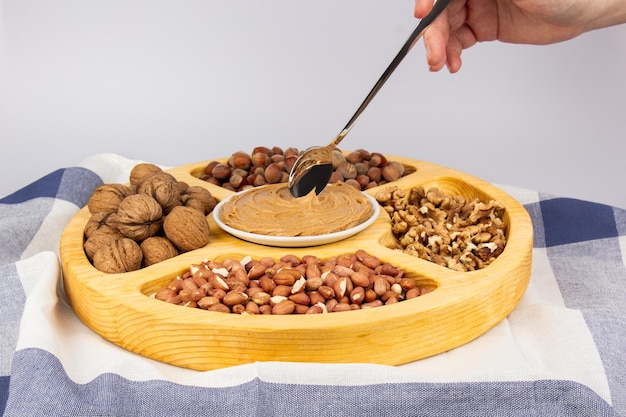 Creamy peanut butter peanut butter in an open glass jar in the center of a peanut food background Peanuts in shell peeled peanuts on a white background Vegan food concept Creamy peanut butter flat