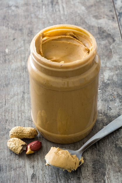 Creamy peanut butter and spoon on wooden surface