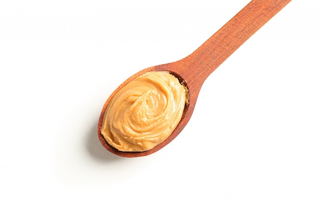 Creamy peanut butter in wooden spoon isolated, top view. A traditional product of American cuisine